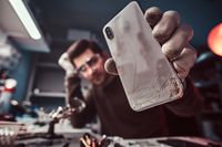 electronic-technician-showing-a-modern-smartphone-with-a-broken-body-in-a-repair-shop
